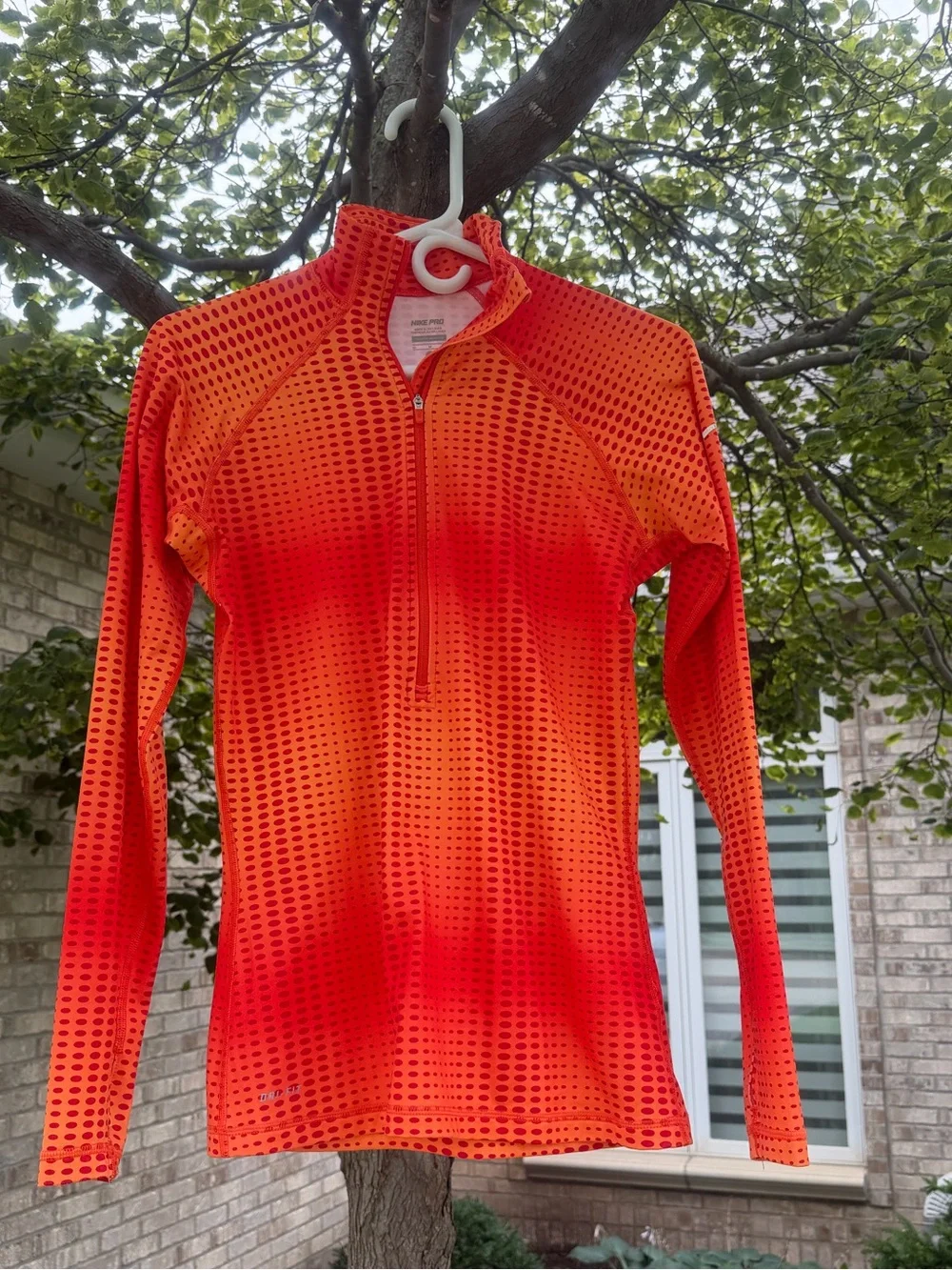 The Nike Pro Hyperwarm half-zip running top features a vibrant orange and red